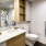 Large well lit bathroom with large mirror and brown cabinets 